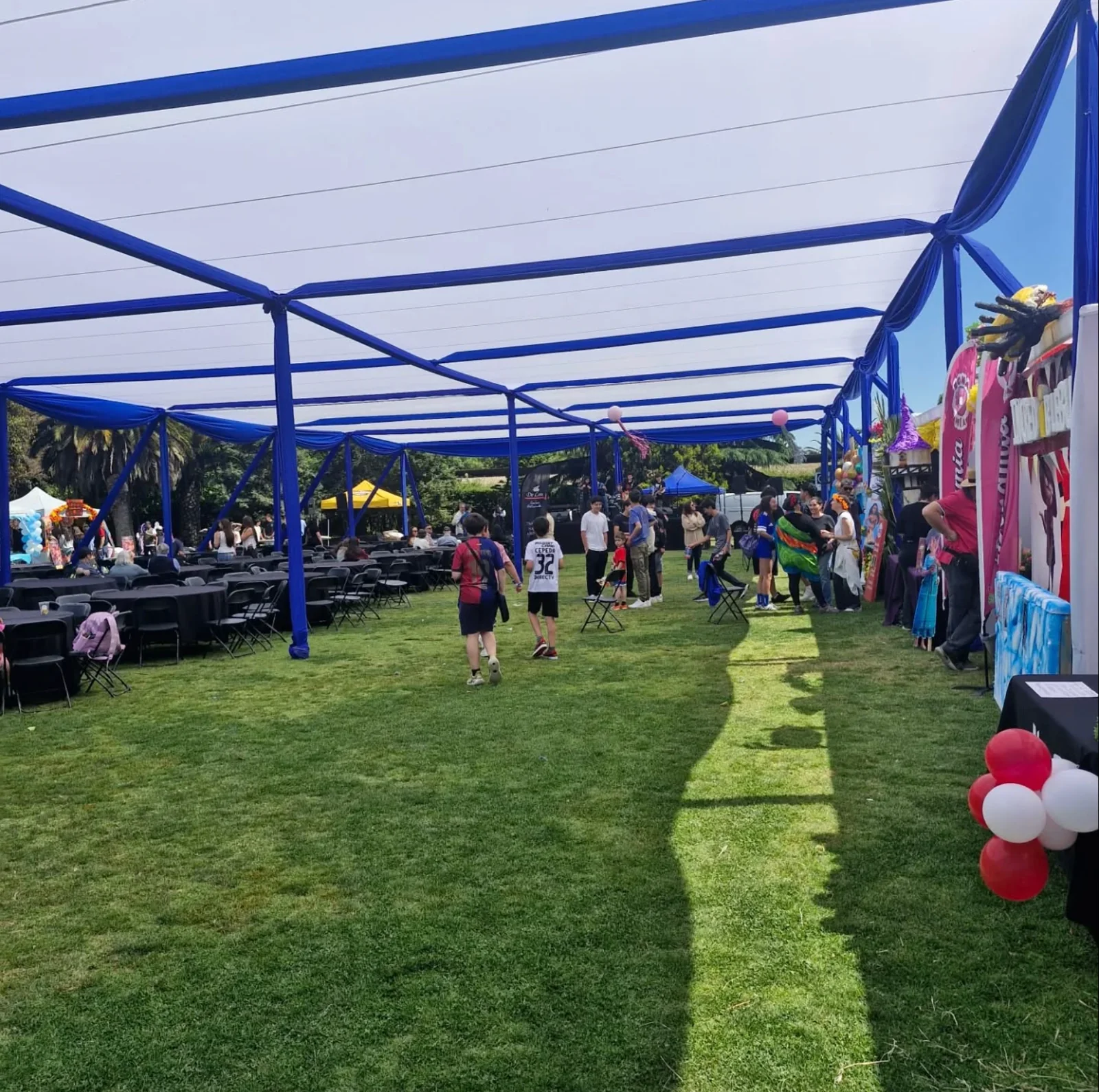 Evento al aire libre bajo una carpa con mesas y asistentes